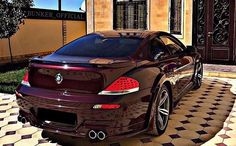 a brown sports car parked in front of a house with black and white checkered flooring