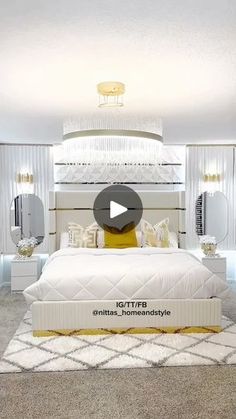 a white bed sitting inside of a bedroom next to two mirrors on the wall and a chandelier above it