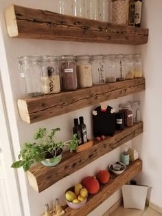 three wooden shelves filled with jars and containers on top of a wall next to a toilet