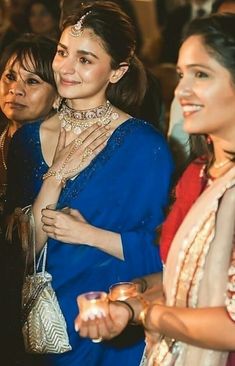 two women standing next to each other with jewelry on their hands and one holding a purse