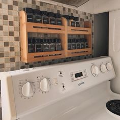 a white stove top oven sitting inside of a kitchen next to a wall mounted spice rack