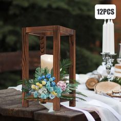 a wooden lantern with flowers and greenery sits on a table