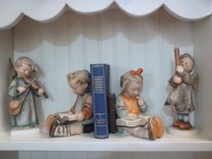 three figurines sitting on top of a shelf next to books and a book