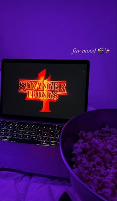 a laptop computer sitting next to a bowl of popcorn