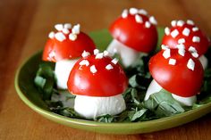 small red mushrooms with white sprinkles on them sit in a green bowl