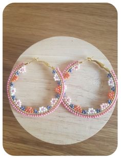 two pairs of beaded hoop earrings sitting on top of a wooden table