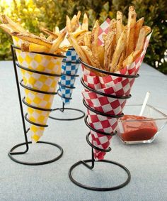 three baskets filled with french fries sitting on top of a table next to a bowl of ketchup