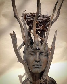 a statue with branches on top of it and a bird's nest in the head