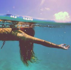 a woman is swimming in the water with her arms stretched out and head above the water