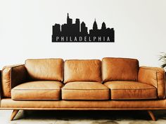 a brown leather couch in front of a white wall with a city skyline on it