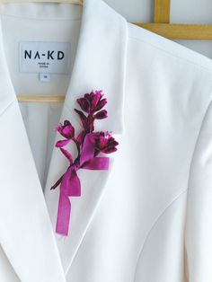 a white suit with pink flowers on the lapel