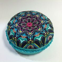 a decorative round case with a colorful design on the front and sides, sitting on a white surface