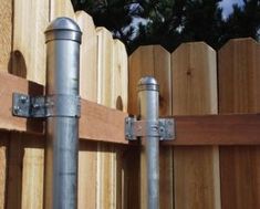 two metal poles are attached to a wooden fence