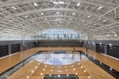 an indoor basketball court with hard wood floors and high vaulted ceilings is seen in this image