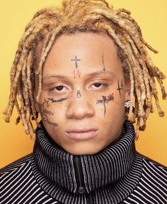 a young man with dreadlocks and tattoos on his face, looking at the camera