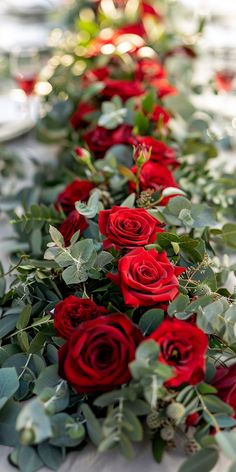 red roses and greenery are lined up on the table