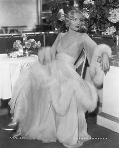 a black and white photo of a woman sitting in a chair wearing a fur stole