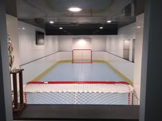 an indoor ice rink with red and white hockey goal on the sidelines, surrounded by metal railings