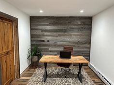 a desk with a laptop on it in front of a wood paneled wall and door