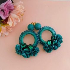 two pairs of blue earrings with flowers on the bottom and green beads hanging from them