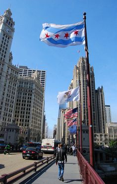 two flags flying in the wind on a bridge