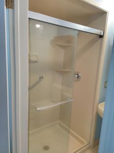 a bathroom with a glass shower door next to a sink and toilet paper dispenser