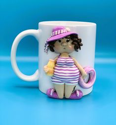 a ceramic figurine sitting on top of a coffee cup with a purple hat