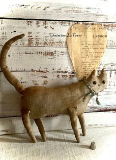 a cat figurine with a wooden heart hanging from it's back end