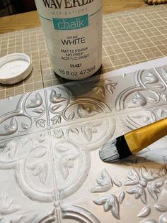 a paintbrush sitting on top of a table next to a white wallpaper design