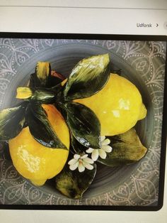 a bowl filled with lemons and flowers on top of a table