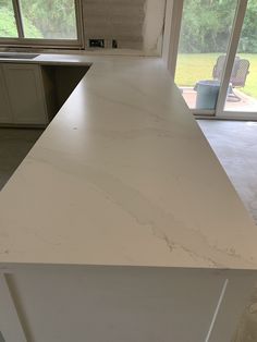 a white counter top in a kitchen next to an open sliding glass door and window