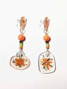 two earrings with orange and white designs on them