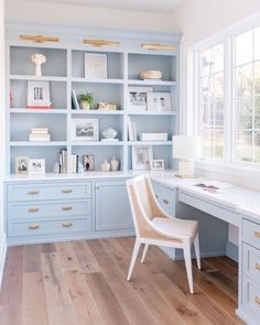 a home office with blue painted cabinets and white desks in front of large windows