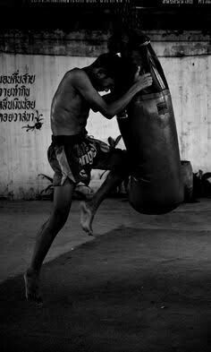 black and white photograph of a man kicking a punching bag