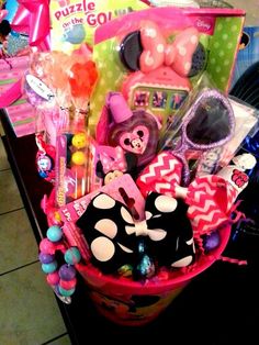 a pink basket filled with lots of toys on top of a counter next to other items