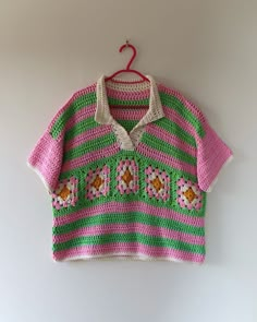 a pink and green sweater hanging on a wall