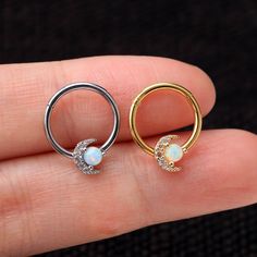 a person is holding two different types of piercings in their hand, one with an opal and the other with a diamond