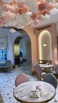 the interior of a restaurant with pink and white flowers hanging from the ceiling above tables