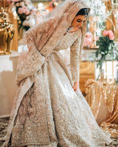 a woman in a white wedding gown and veil is standing on the floor with her hands behind her head