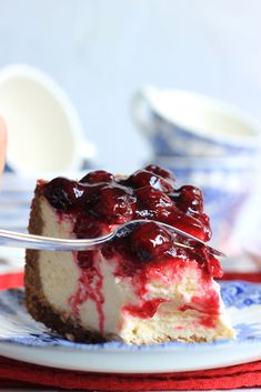 a piece of cheesecake with berries on top is being held up by a fork