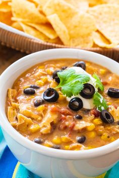 a white bowl filled with mexican chicken soup and tortilla chips on the side