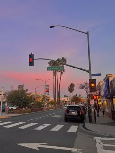 a street with cars parked on the side of it and palm trees in the background