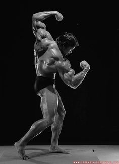 a bodybuilding man flexing his muscles in black and white, with one arm extended