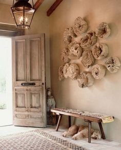 a wooden bench sitting in front of a door next to a wall mounted with seashells