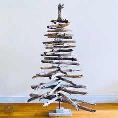 a wooden christmas tree made out of driftwood on a wood floor in front of a white wall