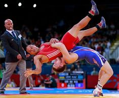 a wrestler is doing a handstand on his opponent