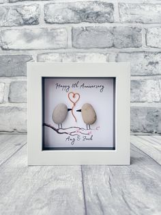 two rocks in a white frame with the words happy anniversary written on them and an orange heart