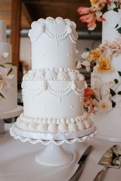 a three tiered white wedding cake sitting on top of a table