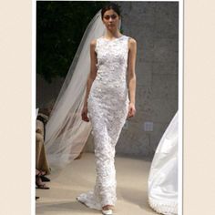 a woman in a white dress and veil walking down the runway