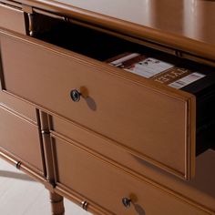 a wooden dresser with two drawers and a magazine on top